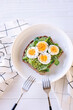 Hard boiled egg on avocado toast with freen leaves, healthy breakfast or lunsh, top view with two forks