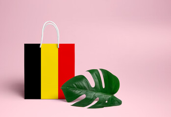 Belgium shopping concept. National cardboard shopping bag with monstera leaf and pink background. Online shopping theme.