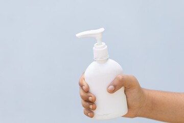 Canvas Print - Person holding a bottle of hand press sanitizer with a grey background