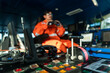 © Igor Kardasov - Filipino deck Officer on bridge of vessel or ship wearing coverall. He is looking through binoculars. COLREG navigaton watch at sea