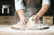 Young woman kneading dough at table in kitchen, closeup