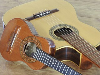 Wall Mural - Close-up of an acoustic guitar and a Brazilian string musical instrument: cavaquinho, on a wooden surface. They are widely used to accompany samba and choro, two popular Brazilian rhythms. Top view.