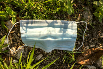 protective face mask on the ground amid grass and stones,concept of coronavirus and pollution