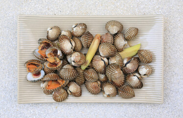 Poster - Boiled cockles on square ceramic plate on marble background