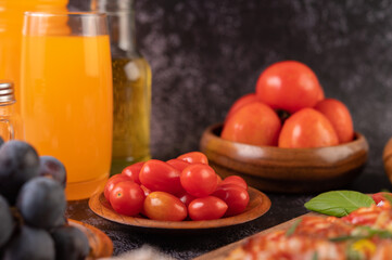 Wall Mural - Fresh tomatoes in a wooden cup, grapes and orange juice in a glass.