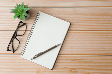 Wall Mural - Top view of Notebooks, pens, glasses, cactus  on wooden desks with sunlight and copy space