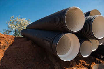 black drainage pipes close up lying in a pile on the ground