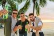 © Syda Productions - friendship and leisure concept - group of happy young men or male friends toasting non alcoholic beer over tropical beach background in french polynesia