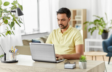 Poster - technology, remote job and lifestyle concept - indian man with laptop computer working at home office