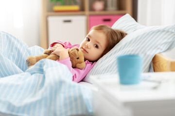 health, children and people concept - sick little girl lying in bed at home