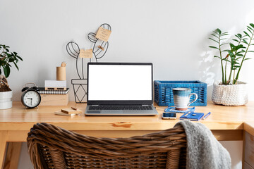 Laptop on office desk with white empty monitor, coffee, plant, phone and pencil. Screen with mockup in office room during work at home. Workplace at home interior. Business and technology.