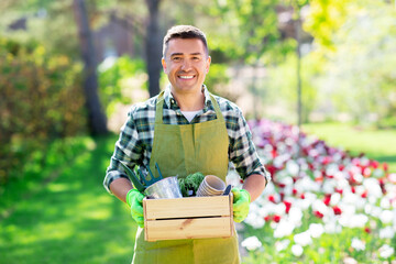 Wall Mural - gardening and people concept - happy smiling middle-aged man in apron with tools in box at summer garden