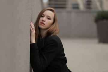 Wall Mural - The girl in black coat. Beautiful emotional young girl in the city. Shawl or handkerchief on a person. 