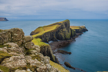 Wall Mural - Small lighthouse barely visible at the tip of Neist Point 