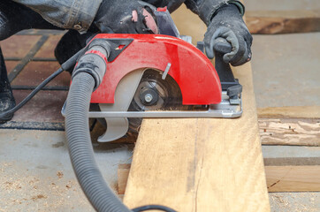 Wall Mural - Carpenter cuts wooden board with hand-held circular saw