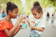 Cute little sisters eating ice-cream in the street