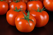 Mehrere knallrote Tomaten auf schwarzem Hintergrund / Saftige reife rote Rispentomaten