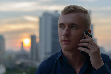 Wall Mural - Portrait of young blond businessman against view of the city