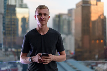 Wall Mural - Portrait of young man with blond hair against view of the city