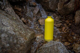 Fototapeta  - Żółta metalowa butelka na wodę stojąca w górskim potoku