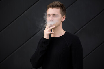 Sticker - Young handsome guy Smoking a cigarette on black background