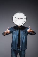 Wall Mural - Man with clock near face showing thumbs up on grey background, concept of time management