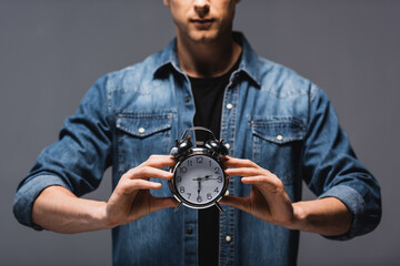 Wall Mural - Cropped view of man holding alarm clock isolated on grey, concept of time management