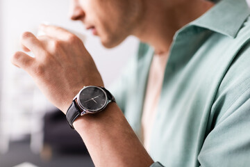 Wall Mural - Cropped view of man in wristwatch drinking coffee, concept of time management