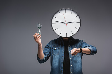 Wall Mural - Man with clock on head, wristwatch and hourglass on grey background, concept of time management