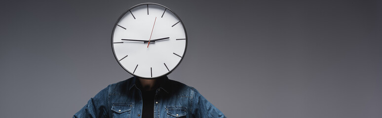 Panoramic shot of man with clock on head on grey background, concept of time management