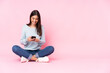 © luismolinero - Young caucasian woman isolated on pink background sending a message with the mobile