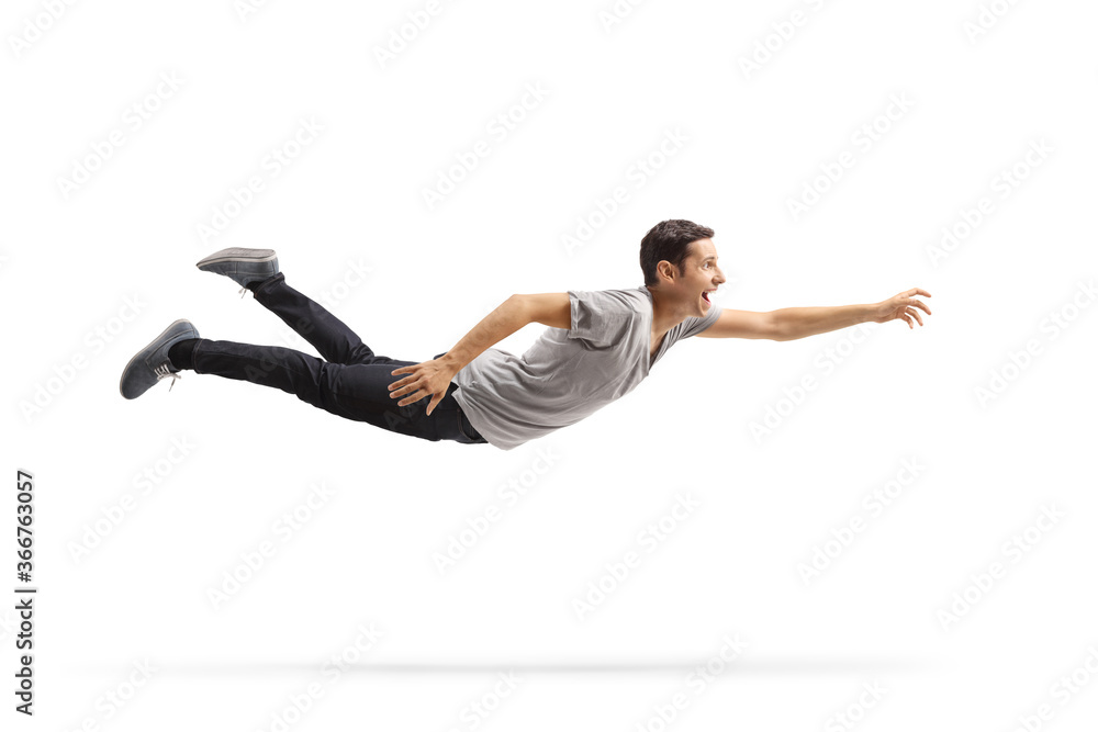 Casual young man flying and reaching for something - obrazy, fototapety, plakaty 
