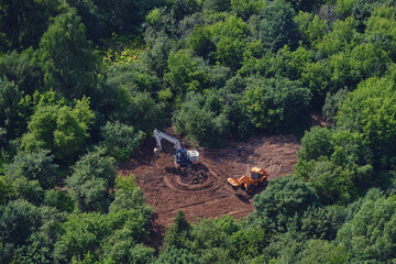 Top view of a park with green trees in which construction equipment works - July 10, 2020, Moscow, Russia