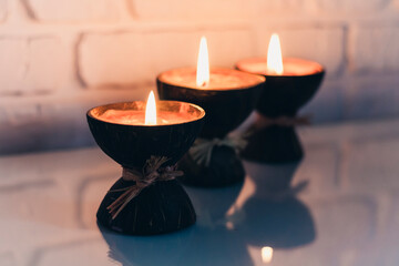 Wall Mural - Burning spa aroma candles in coconut shell on a glass white table, cozy home interior.