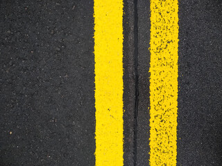 Close-up yellow dividing lines on the road with copy space. Yellow double solid line. Road markings on asphalt. Gray asphalt background with two yellow road lines.