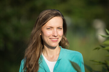 portrait of a young woman with long hair, natural woman outdoor portrait over green grass park backg