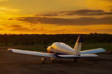 Rear View Of A Parked Small Plane On A Sunset Background. Silhouette Of A Private Airplane Landed At Dusk.