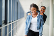 © AS Photo Family - Two african woman friends in jeans jacket having fun, jumped on shoulders indoor together.