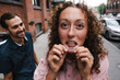 © Jake Jakab/ADDICTIVE STOCK - Cheerful female with curly hair showing tattoo on lips during city walk with boyfriend in New York