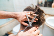 © Pol Sole/ADDICTIVE STOCK - Back view of unrecognizable male making haircut to guy using scissors against blurred interior of light bathroom at home
