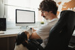 © Raquel Arocena/ADDICTIVE STOCK - Side view of serious male entrepreneur sitting on office chair and looking at cute dog during remote work