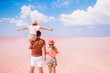 © travnikovstudio - Family walk on a pink salt lake on a sunny summer day.