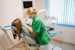 © Victor Bordera/ADDICTIVE STOCK - Focused middle aged professional doctor in green uniform examining oral cavity of woman in dentist chair