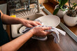 Woman wiping dishware with cotton towel in kitchen