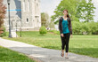 Beautiful female student, with red hair, wearing backpack on campus - walking down path