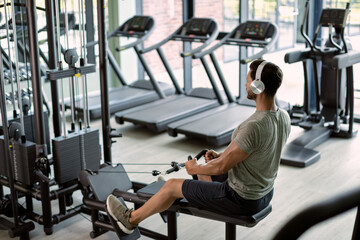 Young sportsman having cross training on rowing machine at health club.