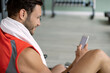 © Drazen - Happy athlete typing text message on mobile phone in a gym.