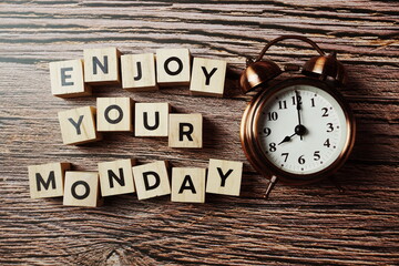 Wall Mural - enjoy your monday alphabet letter with alarm clock on wooden background