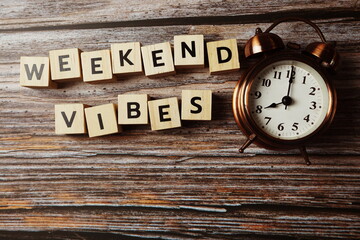 Wall Mural - weekend vibes alphabet letter with alarm clock on wooden background;