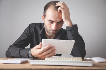 Poster - Caucasian businessman looking his digital tablet in office.